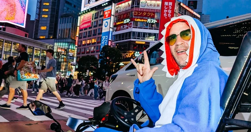 東京のにぎやかな交差点で小さな公道カートに乗るコスチューム姿のドライバーと、後ろを行き交う歩行者